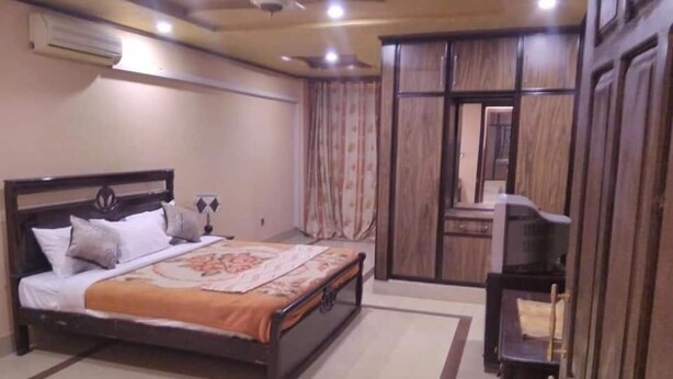 Quarto com cama, guarda-roupa e televisão.