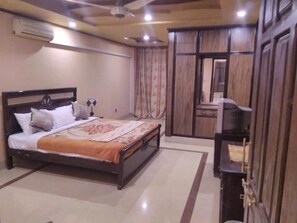 A bedroom with a bed, a wardrobe, and a television. - Hotel Pyramid International (Islamabad)