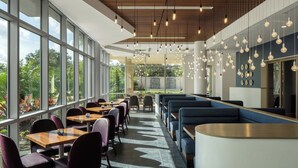 A modern restaurant with large windows, wooden ceiling, and hanging pendant lights. - The Celeste Hotel, Orlando, a Tribute Portfolio Hotel (Orlando)