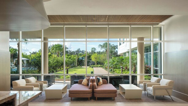 A modern lobby with large windows, a seating area with sofas and chairs, and a view of a lush garden. - The Celeste Hotel, Orlando, a Tribute Portfolio Hotel (Orlando)