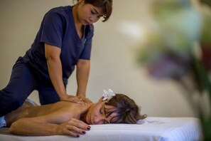 Sesión de masoterapia en curso sobre una camilla con sábana blanca.