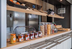A counter with various food items, including jars of preserves and a bread basket. - B&B HOTEL Colmar Expo (Colmar)