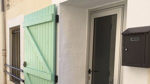 Una entrada de edificio con un portón verde, uno de metal y una puerta con un panel de vidrio.