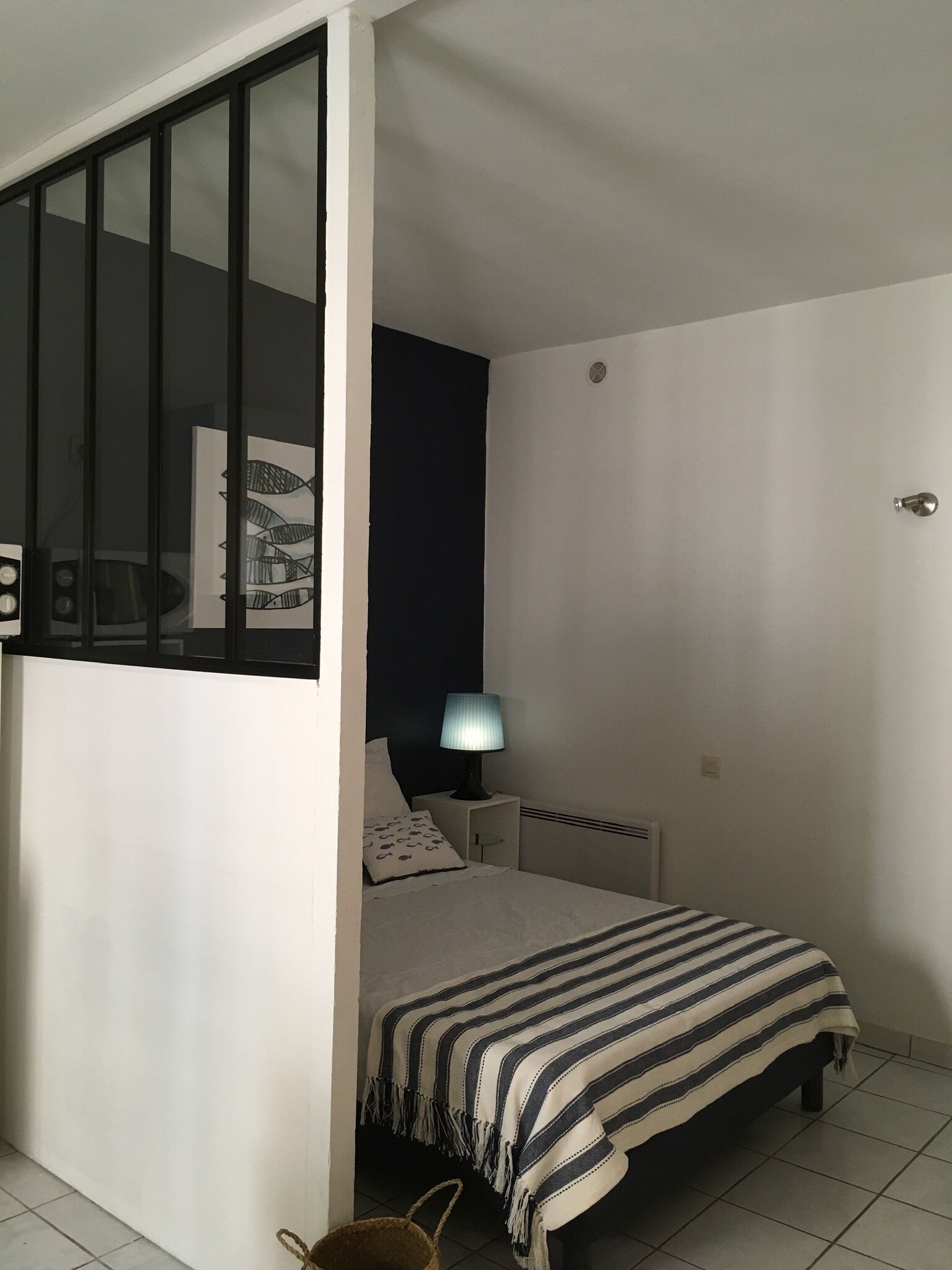 Une chambre à coucher comprenant un lit, une table de chevet, une lampe et un radiateur fixé au mur.