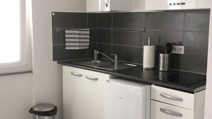 Una cocina moderna con armarios blancos, encimeras negras y un cubo de basura de acero inoxidable.