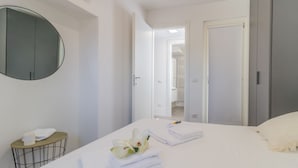 A modern hotel room with a large bed, a round mirror, a bedside table with a lamp, and a view into the bathroom. - La Terrazza di Marta (Varenna)