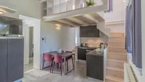 A modern kitchen with a dining area, a staircase, and a built-in bookshelf. - La Terrazza di Marta (Varenna)