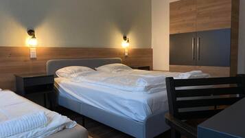 A hotel room with a bed, bedside tables, a desk, and a wardrobe.