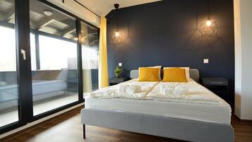 Un dormitorio moderno con una cama grande, dos mesitas de noche y vistas a través de un ventanal.
