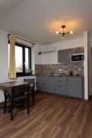 Uma cozinha moderna com armários cinza, uma mesa de jantar de madeira e uma janela com cortinas amarelas.