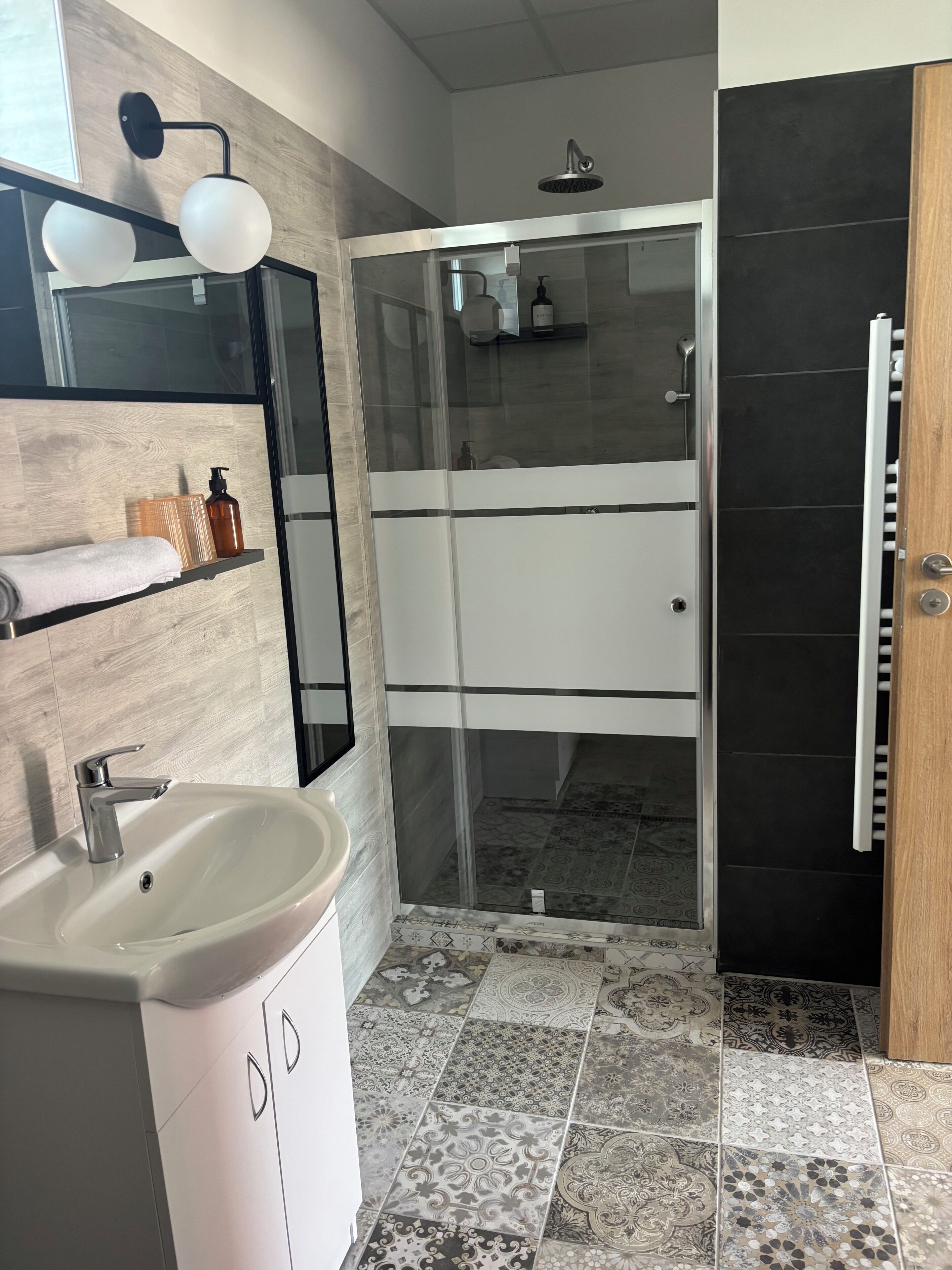 Un bagno moderno con lavandino, specchio, doccia e pavimento piastrellato.