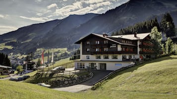 Un hôtel de style alpin traditionnel, doté d’un balcon imposant et offrant une vue sur les montagnes environnantes.