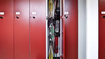 Een rij lockers met de nummers 7 tot en met 12, een paar ski's die tegen de lockers aanleuningen, en een paar schoenen ervoor.