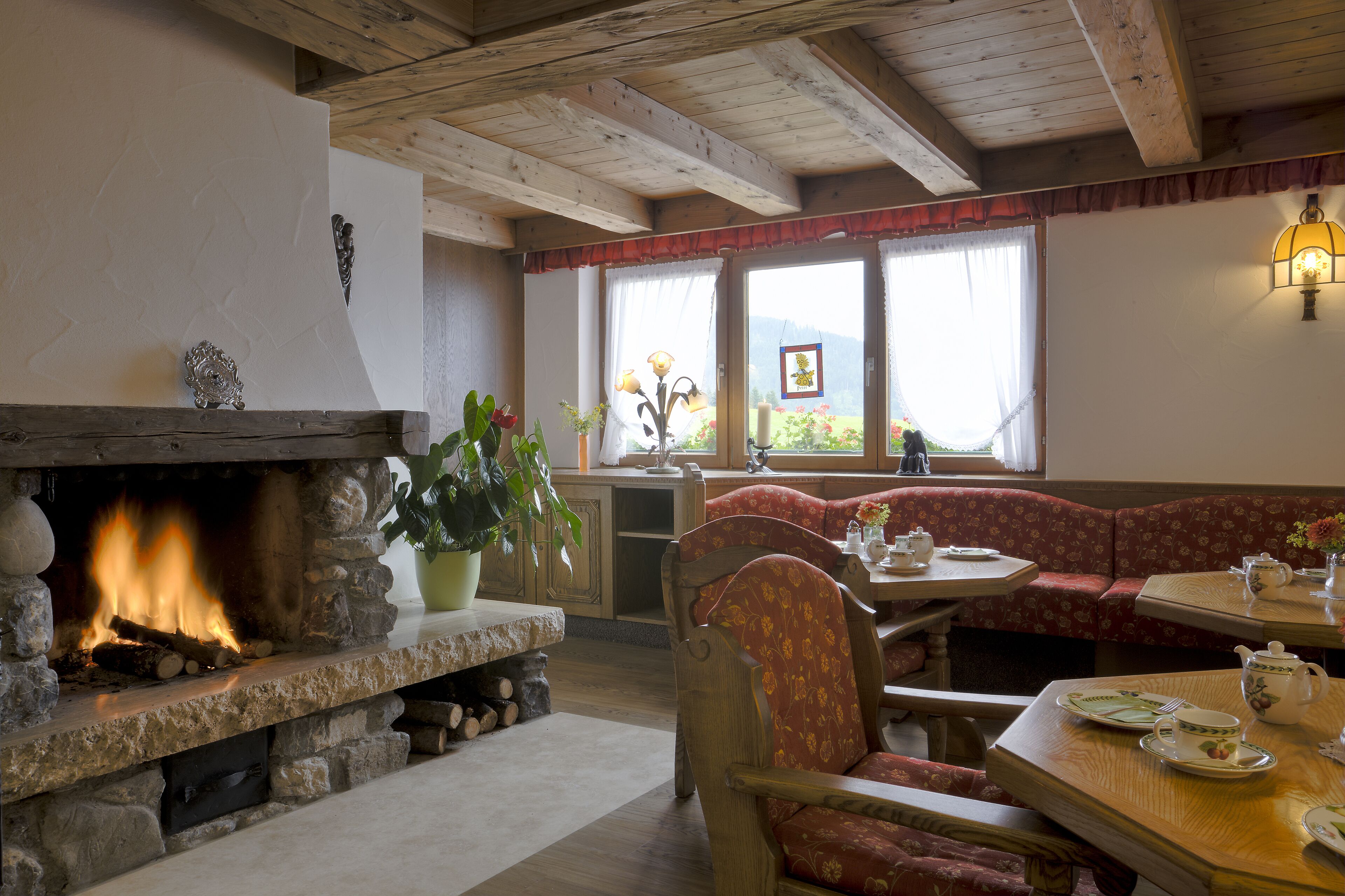 A cozy room with a stone fireplace, wooden beams, a bench, and a table set for tea.