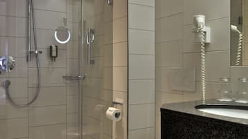 A modern bathroom with a glass-enclosed shower, a toilet, and a sink with a granite countertop.