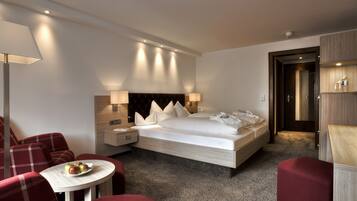 Habitación de hotel con cama, mesita de noche, lámpara, silla y una pequeña mesa con manzanas.