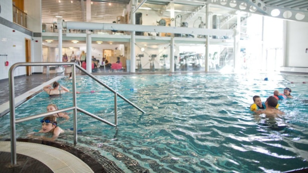 An indoor swimming pool with multiple lanes, a central staircase, and a high ceiling with circular cutouts. - Sherwood Lodge - South Lakeland Leisure Village (Carnforth)