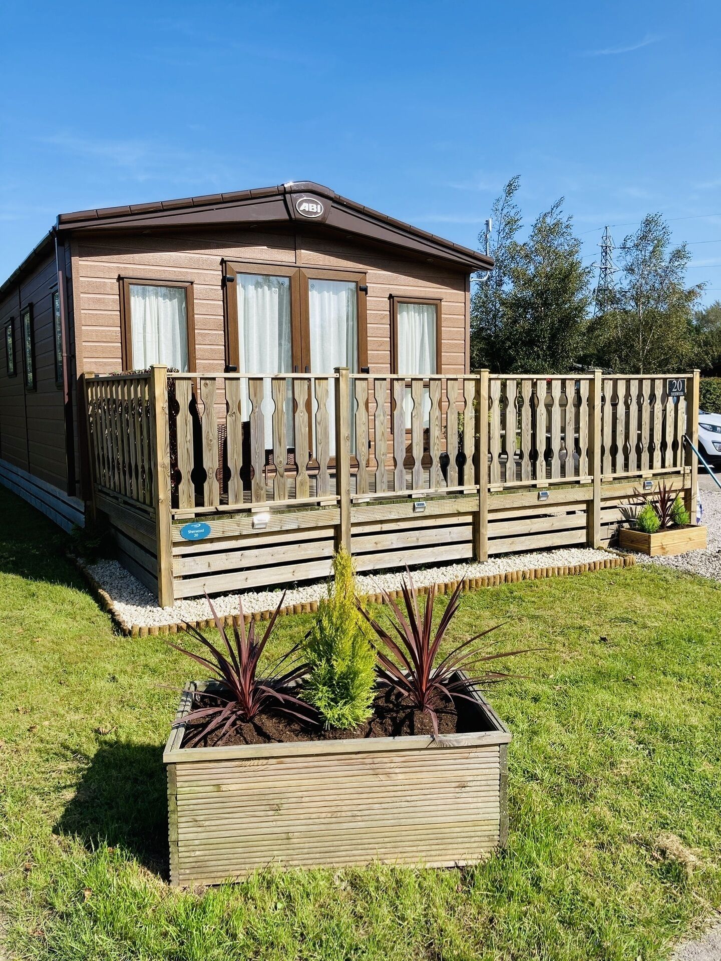 A mobile home with a wooden deck and a fenced area.
