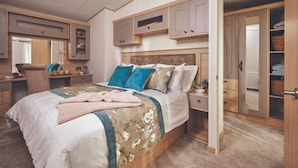 A bedroom with a bed, bedside tables, a wardrobe, and a mirror. - Sherwood Lodge - South Lakeland Leisure Village (Carnforth)