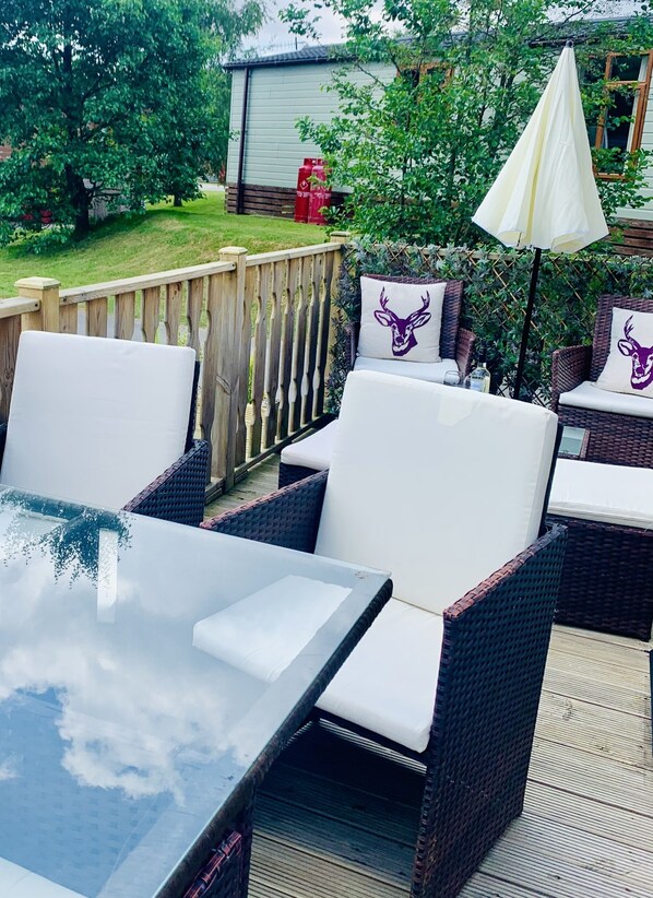 An outdoor patio with wicker furniture, a glass table, and a white umbrella. - Sherwood Lodge - South Lakeland Leisure Village (Carnforth)