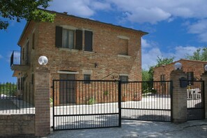 Un immeuble à deux étages en briques, doté d’une entrée fermée par un portail, d’un balcon et d’une antenne parabolique.