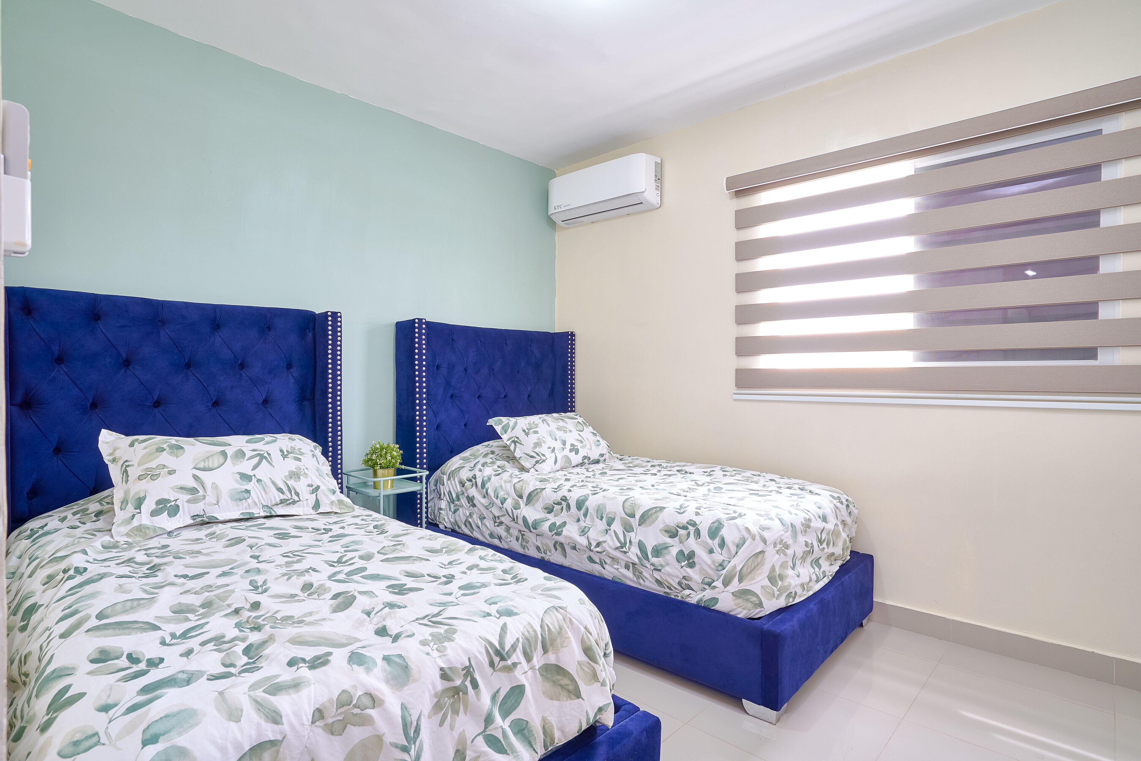A bedroom with two beds, each with a blue headboard and floral bedding.