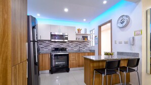 Une cuisine moderne dotée d’appareils électroménagers en acier inoxydable, d’un revêtement mural en carreaux et d’armoires en bois.