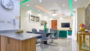 Un salon moderne comprenant un coin repas, un îlot de cuisine et un téléviseur fixé au mur.
