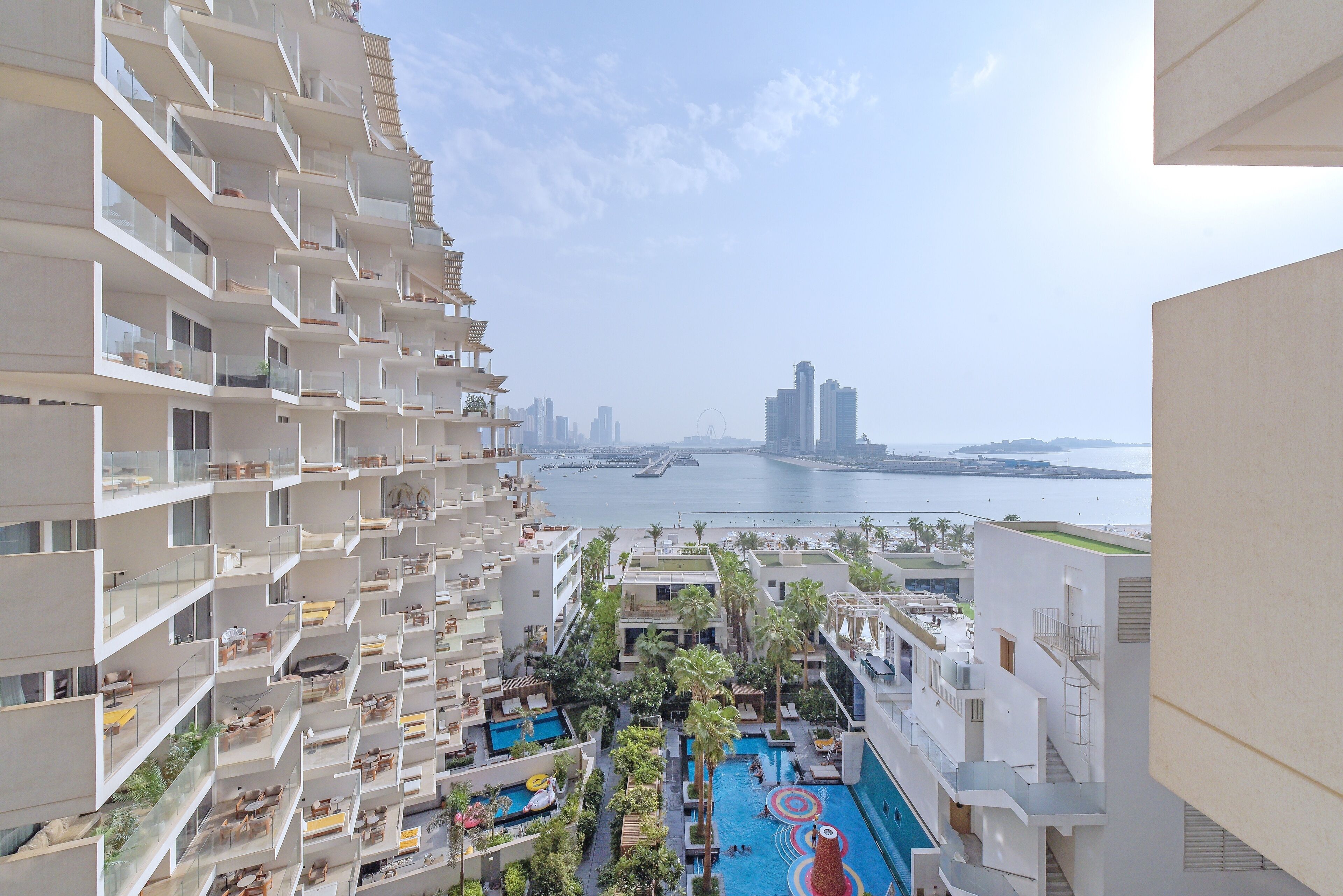 Un hôtel de grande hauteur doté de nombreux balcons, d’une piscine sur le toit et offrant une vue sur la mer et le paysage urbain.