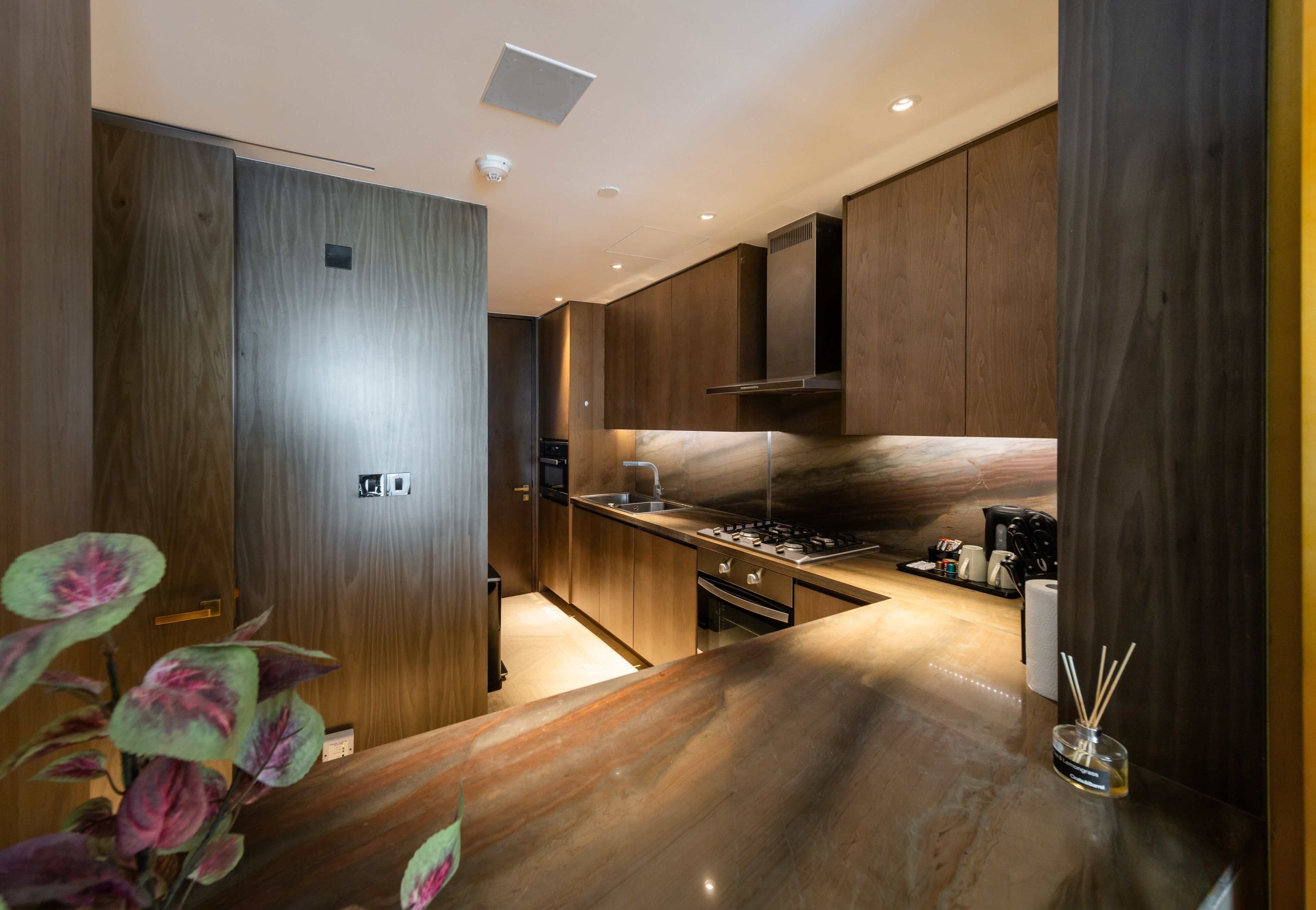 Una cocina moderna con armarios de madera, encimera de mármol y estufa integrada.