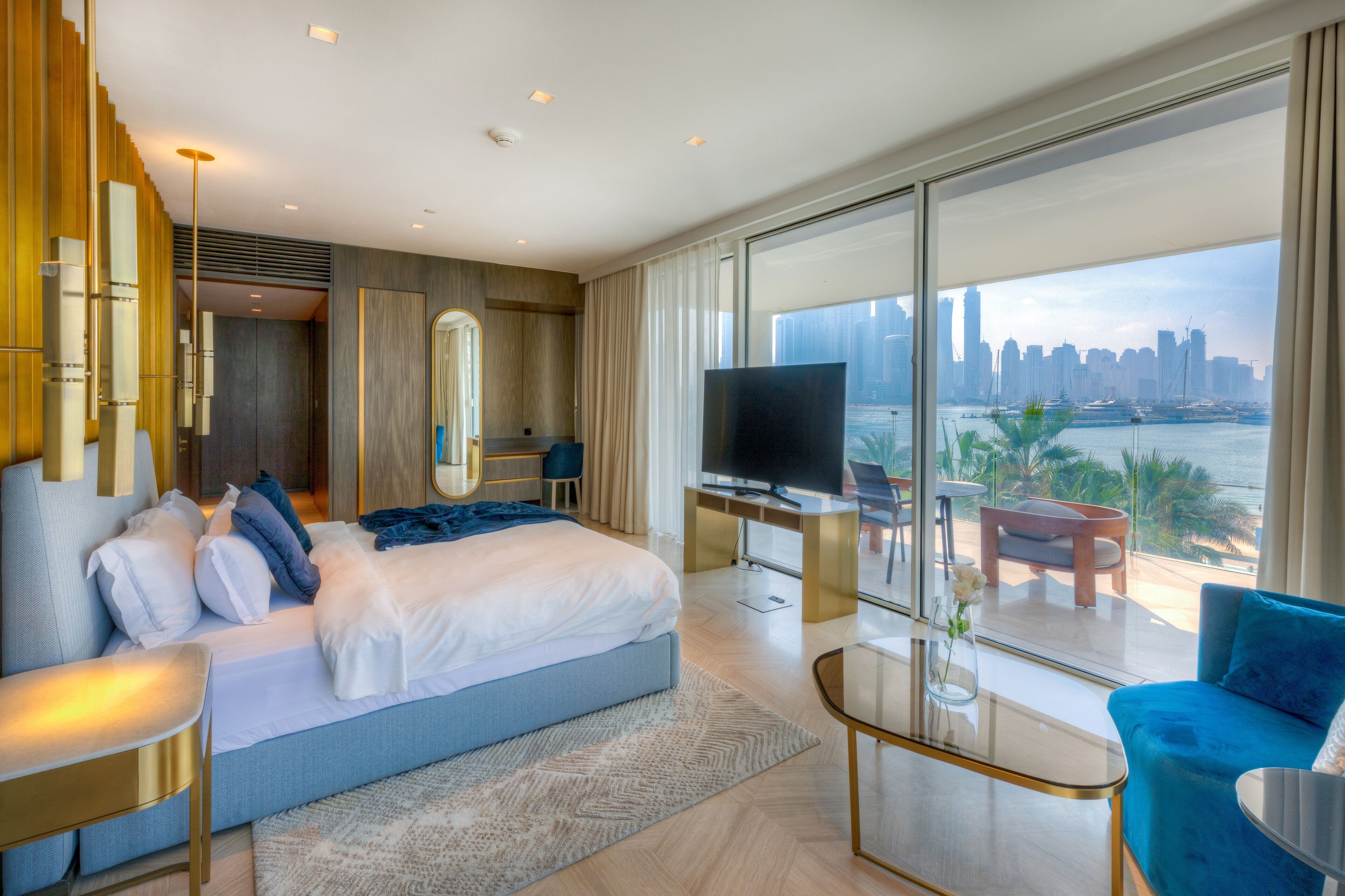 Een moderne hotelkamer met een groot bed, een televisie, een balkon met uitzicht op de stad en een bureau met stoel.