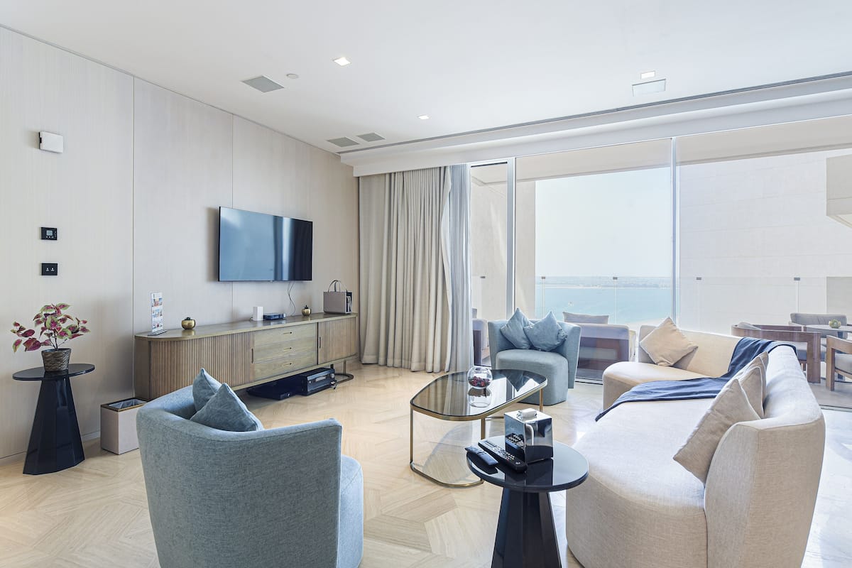 Una sala de estar moderna con un sofá, sillones, una mesita de centro y un televisor montado en la pared.