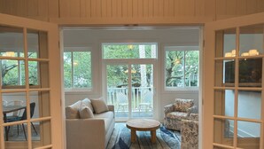 Un espacio habitable de concepto abierto con sofá, sillón, mesa de centro redonda, ventanas amplias y vistas al exterior.