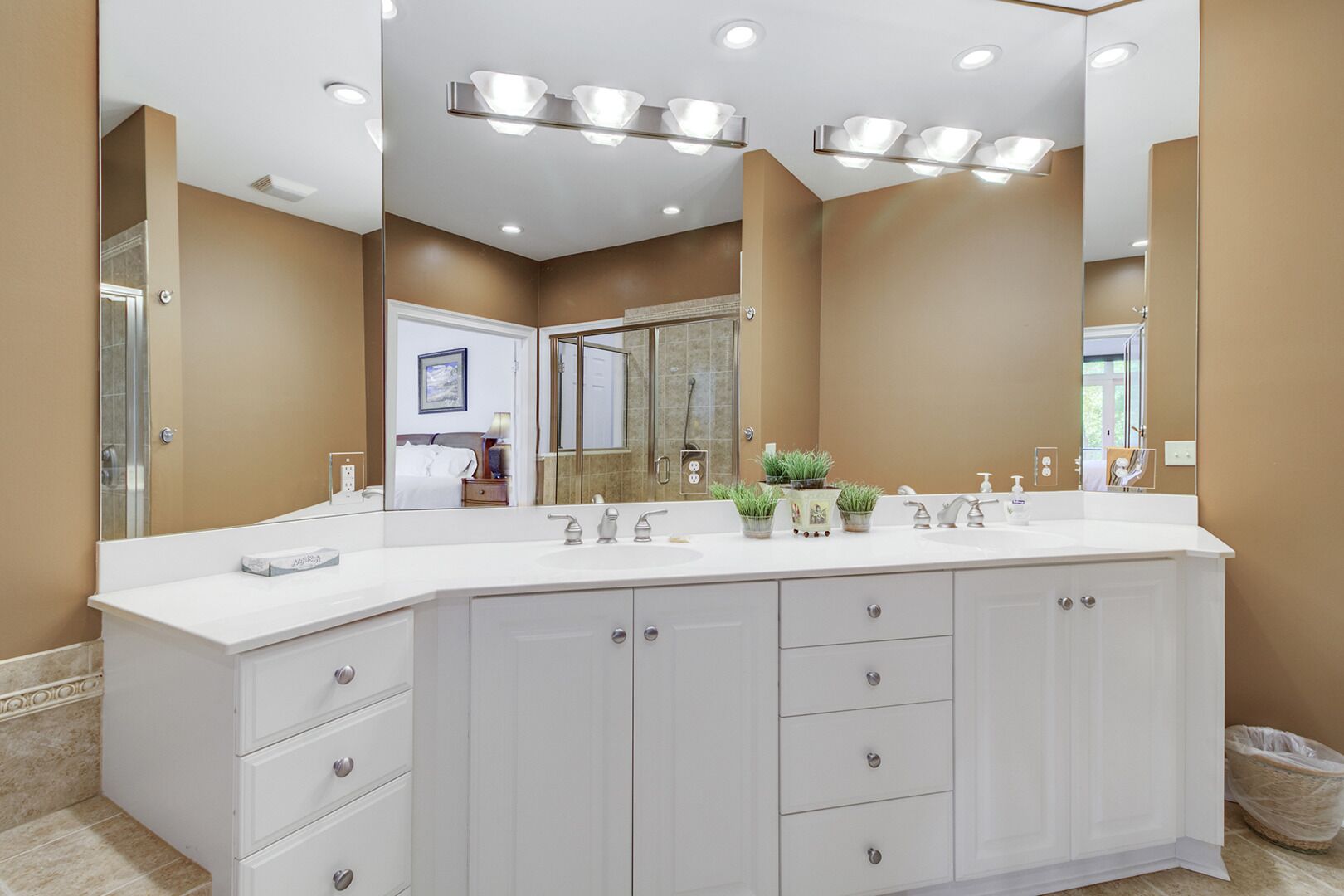 A modern bathroom with a large vanity, multiple sinks, and a large mirror.