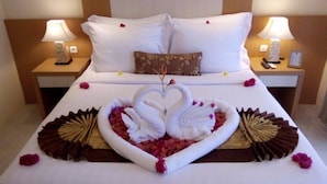 A hotel room with a neatly made bed, two bedside lamps, and a decorative centerpiece of swans made from towels and flowers. - Hotel San Marino (Kitui)