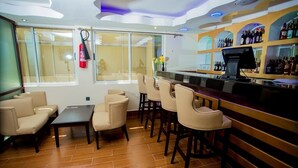 A bar area with a counter, bar stools, and a seating area with a sofa and chairs. - Hotel San Marino (Kitui)