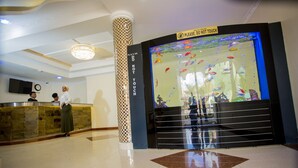 A lobby with a reception desk, a large aquarium, and a 'Do Not Touch' sign. - Hotel San Marino (Kitui)