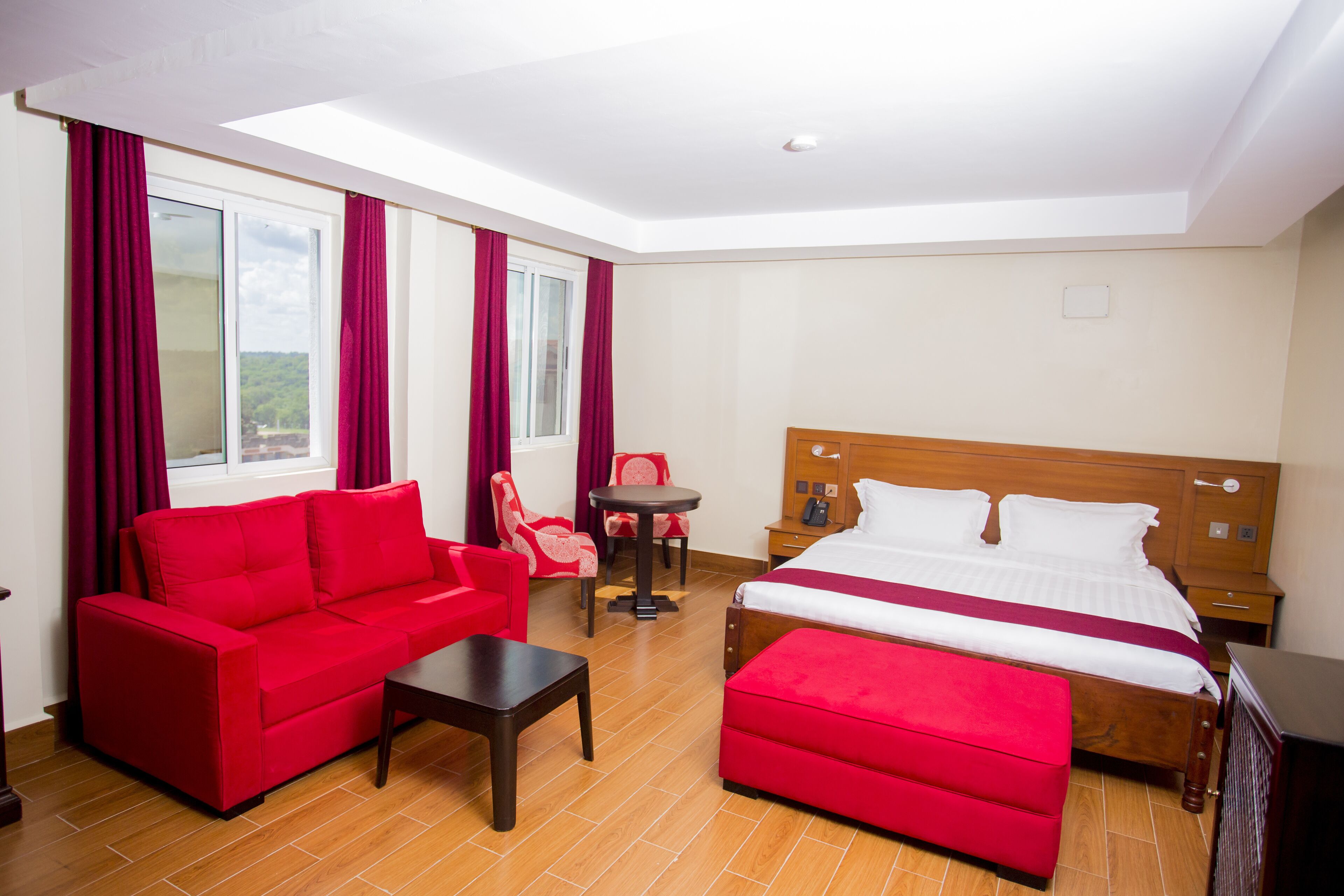 Une chambre d’hôtel avec un lit, un canapé rouge, une petite table et un fauteuil rouge.