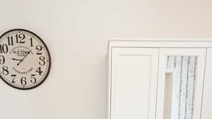 Une chambre à coucher avec un lit, une armoire blanche et une horloge murale.