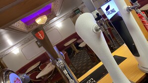 Una zona de bar con un grifo de cerveza, un letrero de neón y una pizarra de menú.