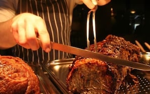 Una persona tallando un gran plato de carne asada.