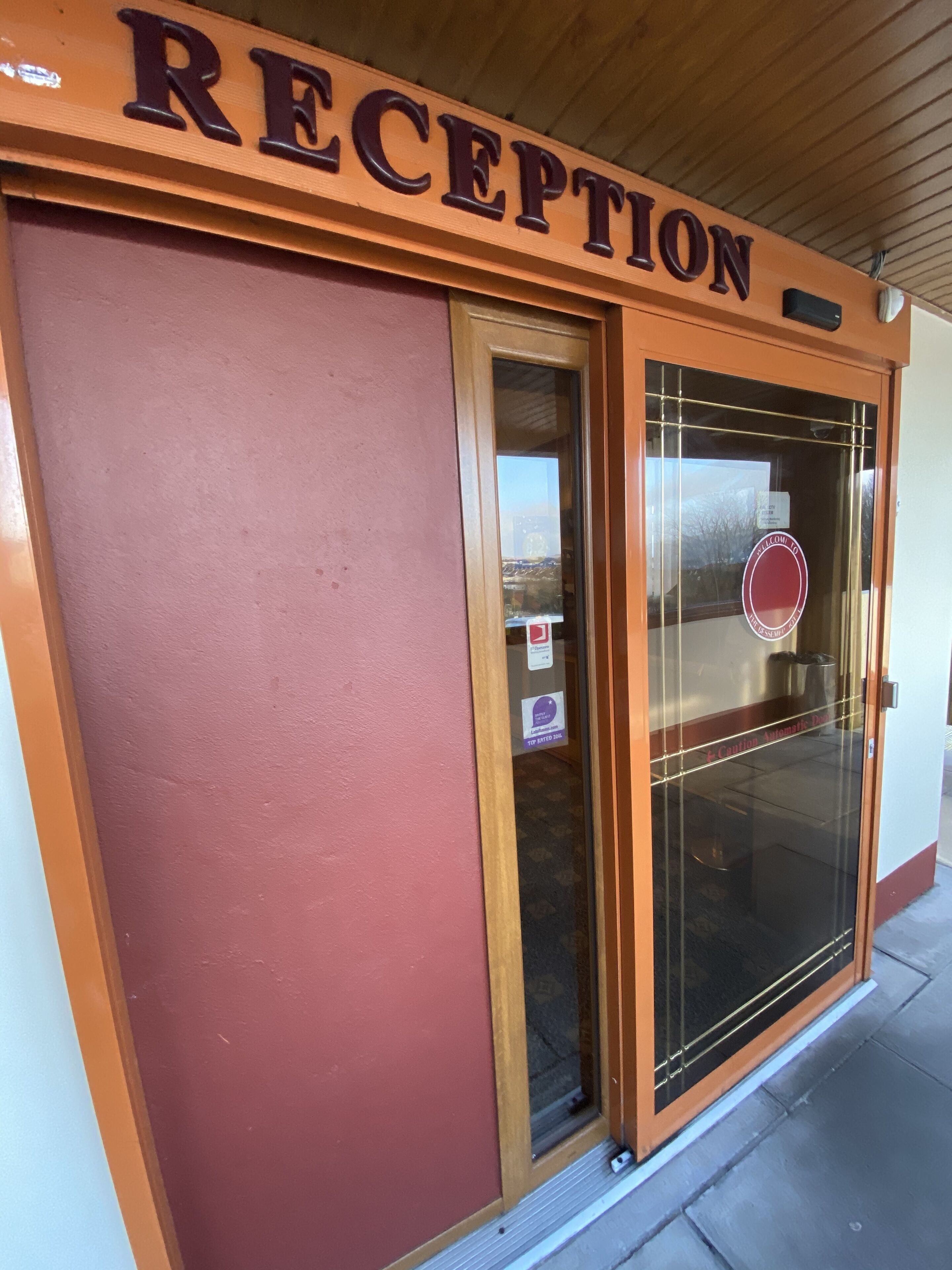 A reception area with a wooden sign above the door and a glass door with a circular logo.