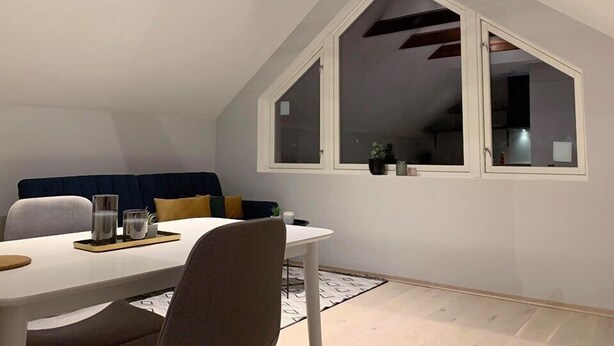 Un comedor con una mesa blanca, sillas marrones y un ventanal con vistas al interior.