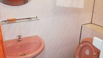 A small bathroom with a pink sink, a toilet, and a mirror above the sink.