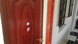Een houten deur met een koperen handgreep en een rookvrij bord.