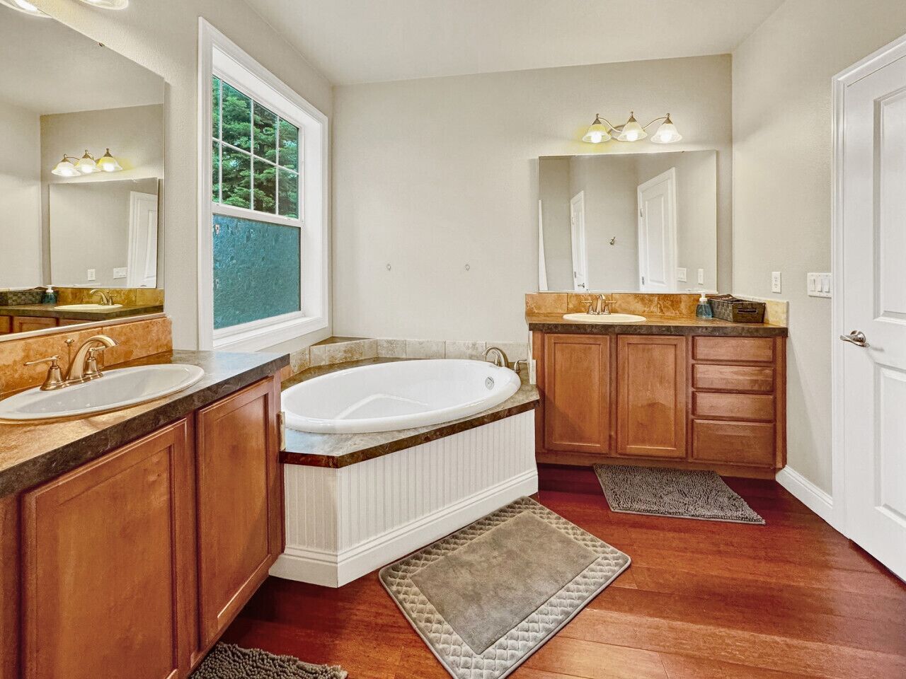 Ein Badezimmer mit einer Badewanne, zwei Waschbecken, Holzschränken und einem großen Spiegel.