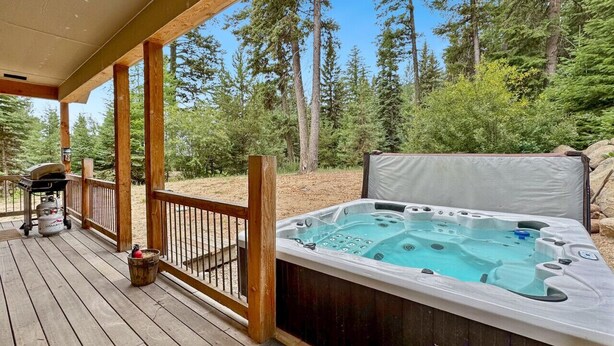 Un bain à remous sur une terrasse en bois, avec vue sur une forêt.