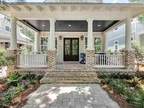 A covered porch with white railings, a brick base, and a dark roof.