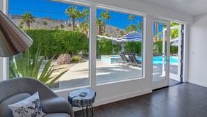 A modern living room with large windows, a pool, and outdoor seating. - Iconic Twin Palms - Classic Upscale Midcentury! (Palm Springs)