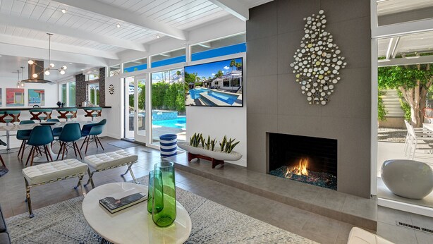 A modern living room with a fireplace, a pool view, and a bar area. - Iconic Twin Palms - Classic Upscale Midcentury! (Palm Springs)